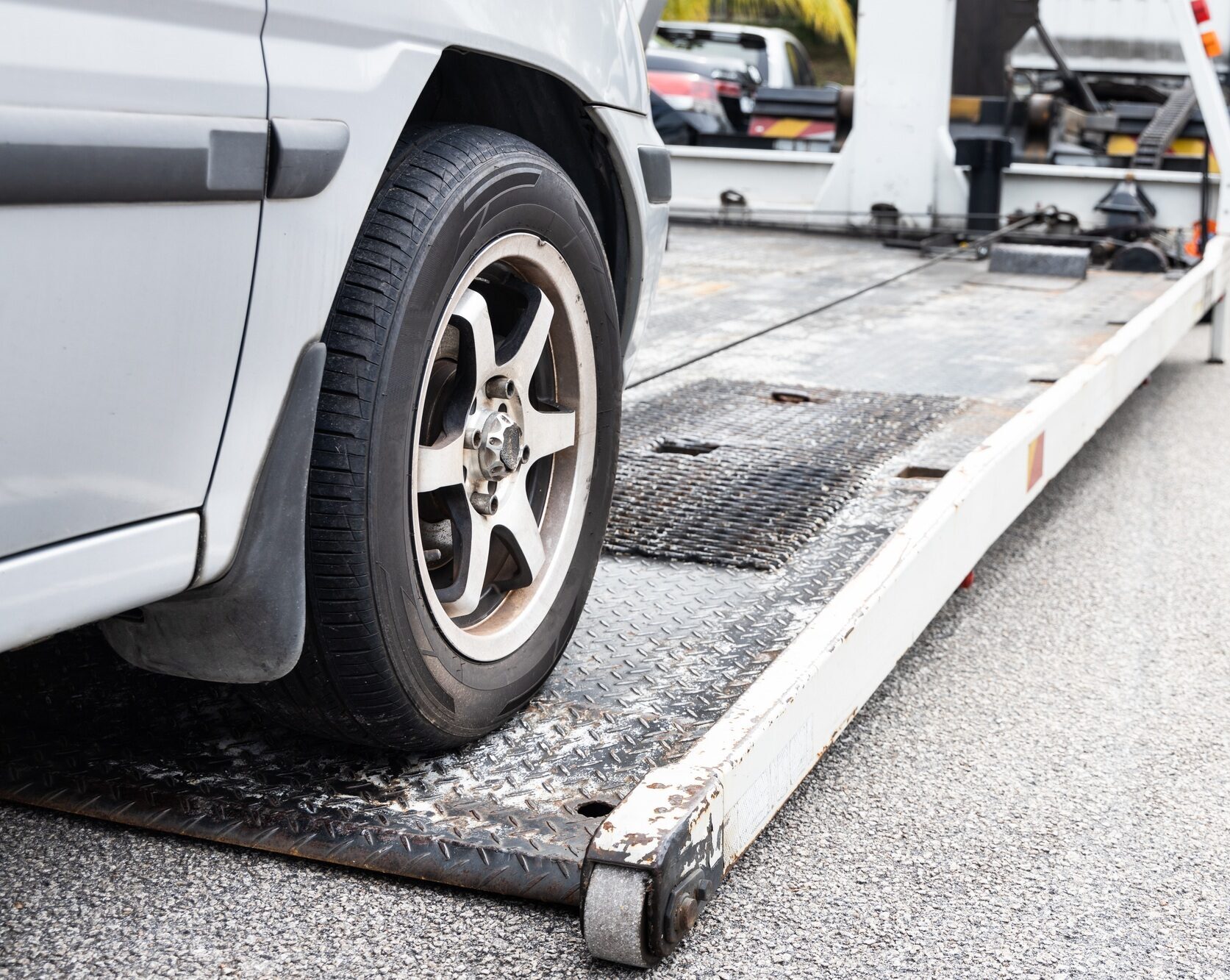 Cable attached to broken down car being pulled onto tow truck